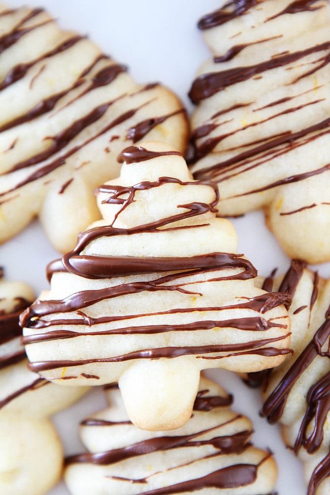 Orange Chocolate Spritz Cookie Recipe on twopeasandtheirpod.com Buttery spritz cookies with a hint of orange and a drizzle of chocolate. These festive cookies are perfect for the holiday season. Orange Chocolate Spritz Cookie Recipe