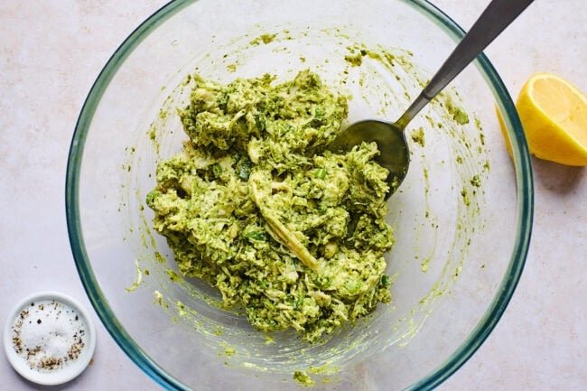 chicken pesto salad in bowl with spoon.