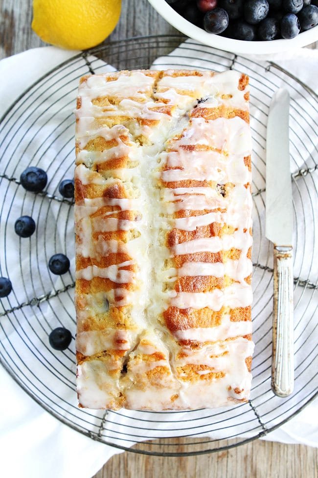 Lemon Blueberry Loaf Cake Recipe on twopeasandtheirpod.com This easy lemon loaf cake is bursting with blueberries! The sweet lemon glaze is the perfect finishing touch! Lemon Blueberry Bread On Plate To Cut