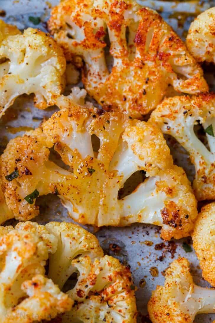 EASY baked crispy cauliflower recipe. You can have this SIMPLE cauliflower recipe ready in under 30 minutes! Sliced cauliflower steaks roasted in butter and seasoning on a baking sheet.