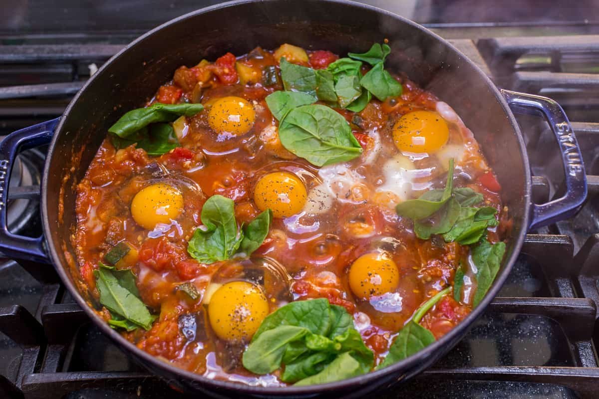 This Eggplant Shakshuka is loaded with zucchini and eggplant in a spicy tomato-based sauce, crowned with egg and fresh spinach. Eggs cracked into shakshuka skillet