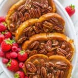 Slices of caramel french toast arranged on a platter with berries scattered
