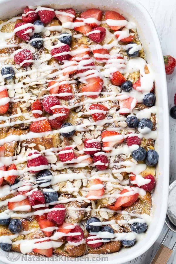 Breakfast French Toast Casserole Recipe in a baking dish with a sieve on he side and fresh berries.