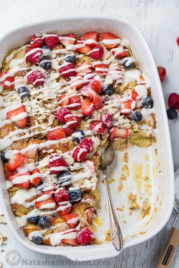 Started French Toast Casserole with a spoon in the casserole and fresh berries on the side.
