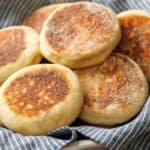 homemade english muffins in a basket with blue striped napkin