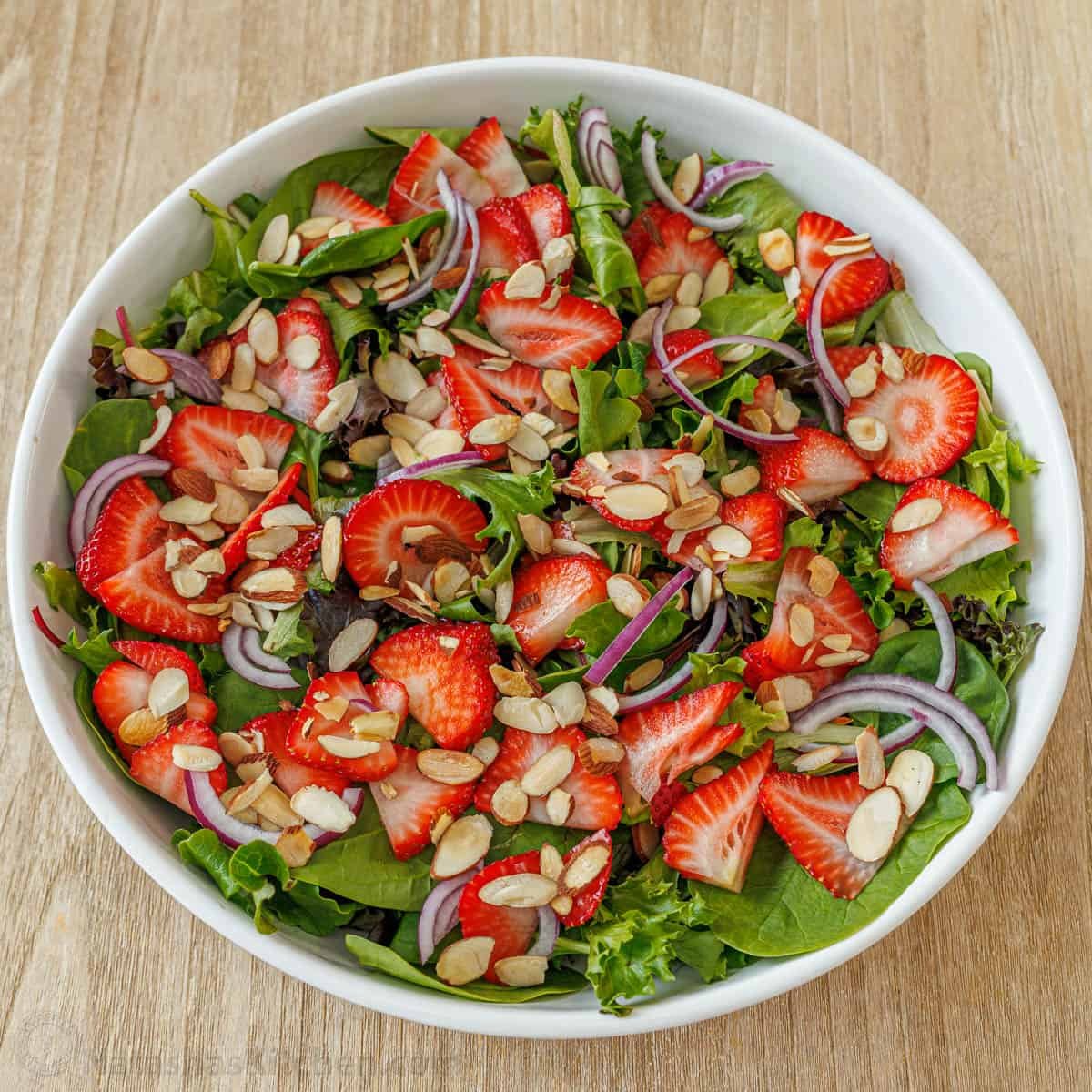Our summer Strawberry Salad with Honey Vinaigrette is both beautiful and delicious with toasted almonds and feta. Serve in just 10 minutes! Side dish with strawberries, toasted almonds, and red onions