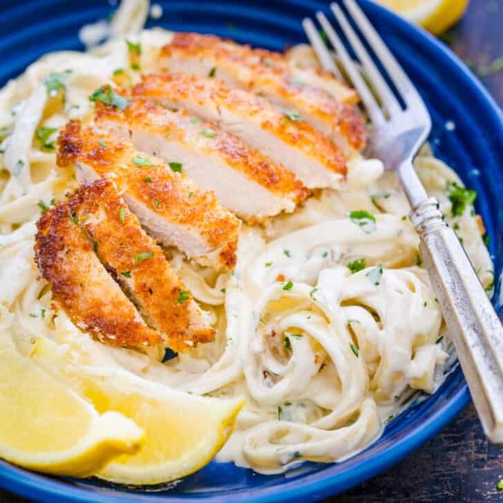 Creamy lemon chicken pasta in blue plate topped with crispy chicken