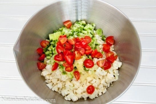Diced cucumbers, cauliflower and halved baby tomatoes in a bowl 