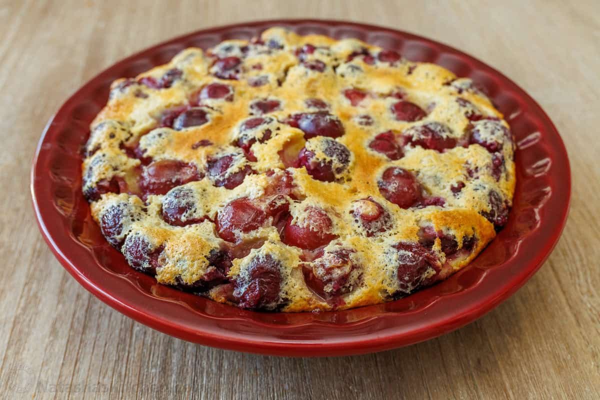 classic cherry clafoutis puffed in a red pie dish