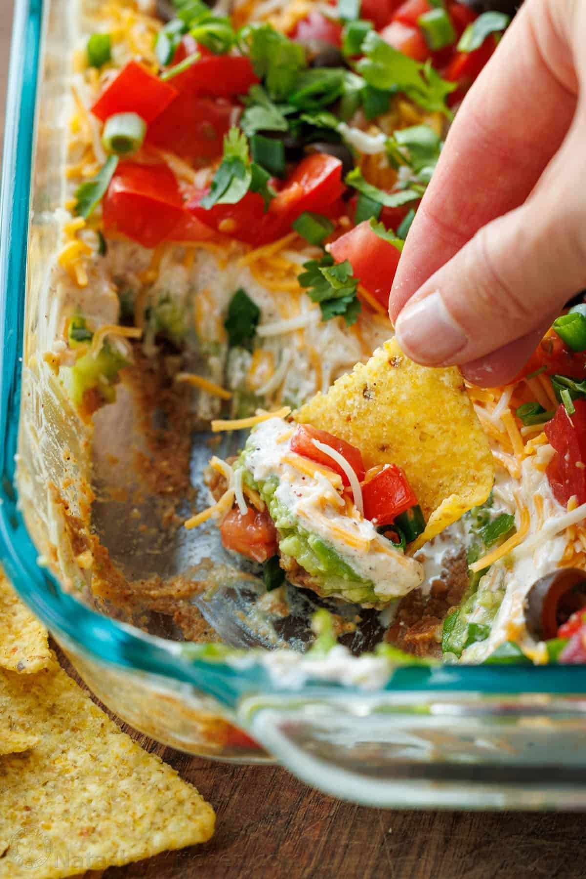 7-Layer Dip being scooped onto a tortilla chip