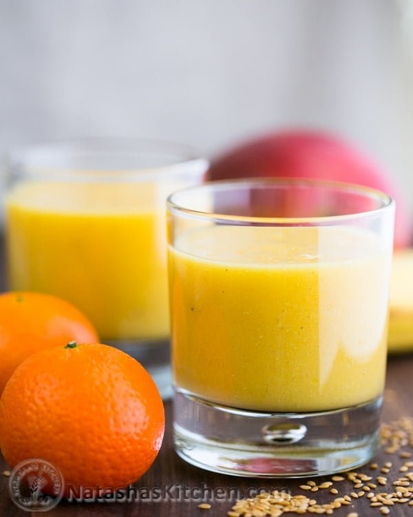 Mango Pineapple smoothie in a cup with fruit scattered