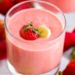 Healthy strawberry smoothie in a glass garnished with strawberry and banana