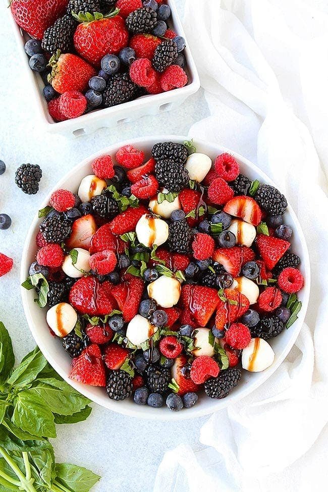 This Beautiful Berry Caprese Salad Is A Great Simple Salad For Summertime! It Only Takes 10 Minutes To Make And Is The Perfect Side Dish To Go With Any Meal! #berry #salad #summer #vegetarian #glutenfree #cheese #basil #easyrecipe #fruit #fruitsalad #easyrecipe #healthyrecipe Berry Caprese Salad with strawberries, raspberries, blackberries, fresh mozzarella, basil, and balsamic glaze in bowl.