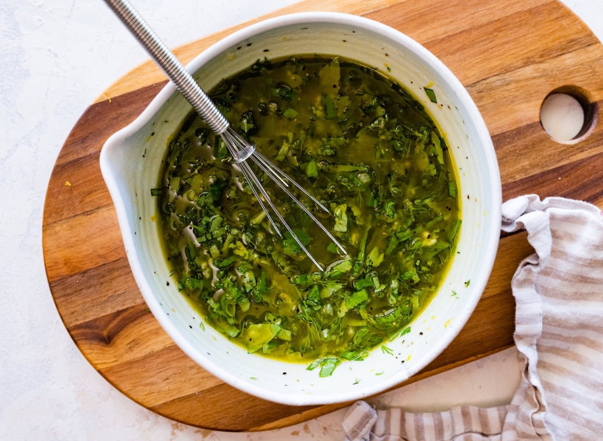 lemon herb dressing in bowl with whisk. 
