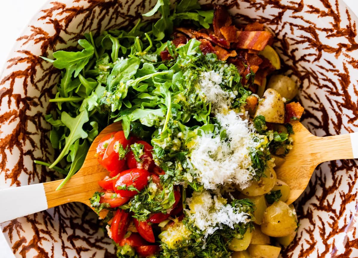 no mayo potato salad being tossed in bowl with salad servers. 