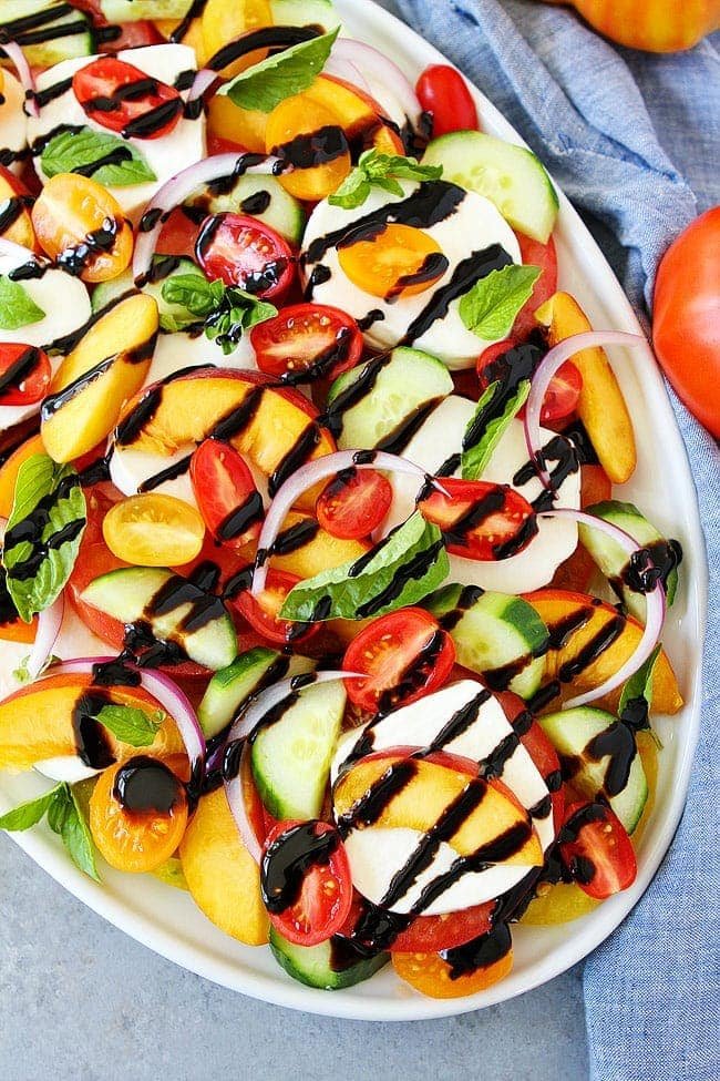 Summer Caprese Salad is an easy side dish that goes great with any summer meal. Summer caprese salad on platter with balsamic glaze