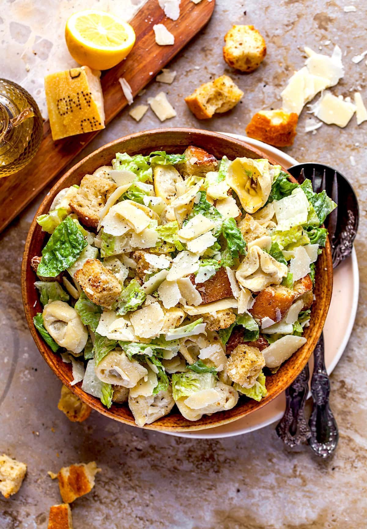 Tortellini Caesar Salad in wood bowl with Parmesan cheese and homemade croutons.