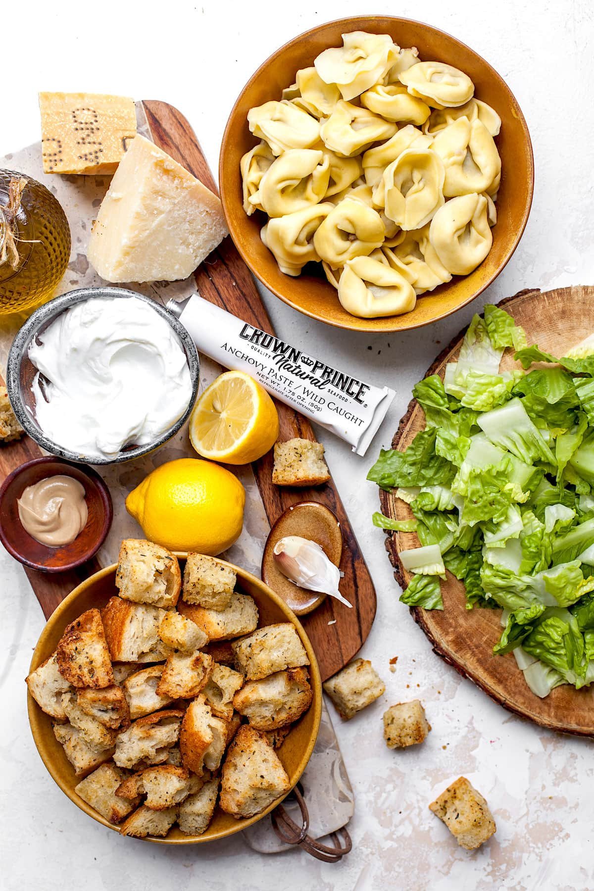 Tortellini Caesar Salad Ingredients in bowls on wood board.