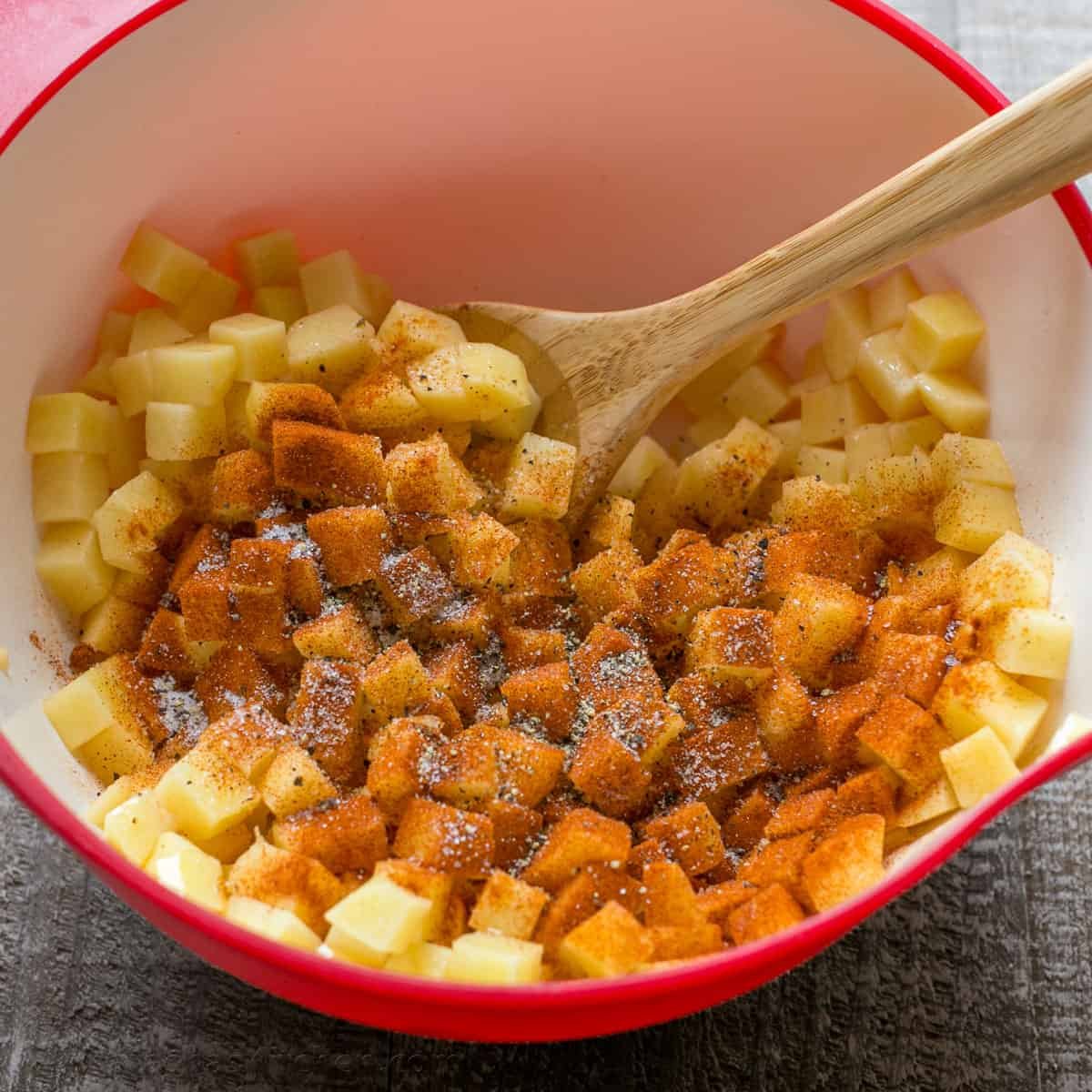 Our go-to, easy breakfast potatoes recipe uses simple ingredients and the best cooking method for potatoes, so each bite is delicious! mixing seasoning into breakfast potatoes using a wooden spoon