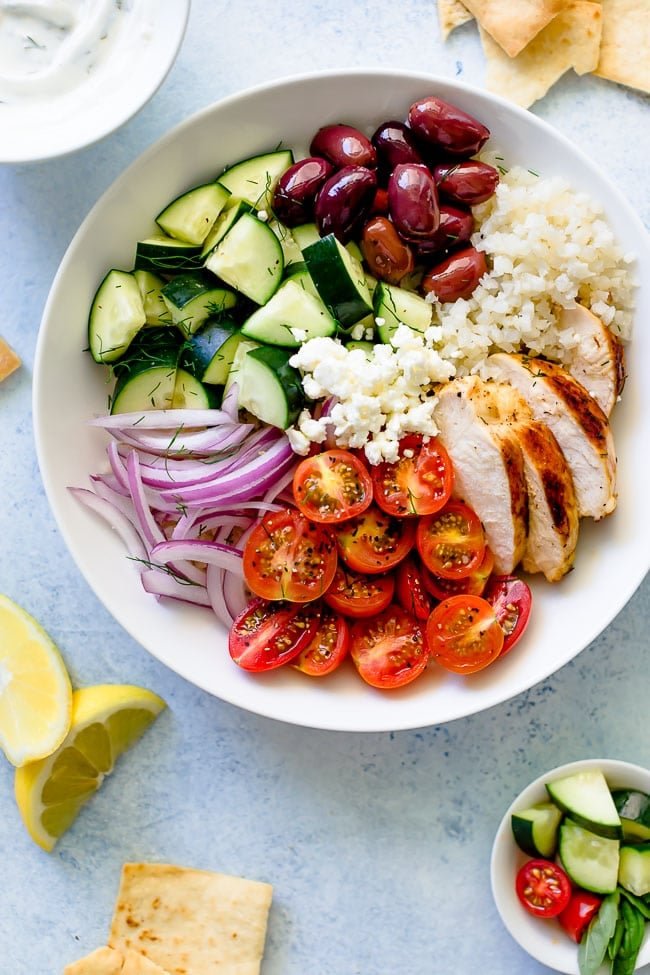 Greek Chicken Bowls Are Made With Lemon Oregano Chicken, Rice, Tomatoes, Cucumber, Olives, Feta Cheese, Red Onion, Fresh Herbs, And Finished With Tzatziki Sauce. These Healthy Bowls Are Great For Lunch Or Dinner. #chicken #chickendinner #dinner #bowls #Greek #healthyrecipe #chickenrecipe #rice #easyrecipe #mealprep Greek Chicken Bowls