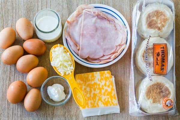 Ingredients for breakfast sandwiches with English muffins, ham, cheese, eggs, sour cream and milk