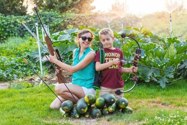 Natasha and her son posing with a crossbow and collecting zucchini