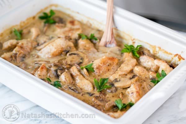 Creamy Chicken Casserole with mushrooms (aka Chicken Gloria) This chicken bake perfect for parties! #chickencasserole #chickenbake #easycasserole #dinner #chicken #mushrooms #casserole #natashaskitchen Creamy chicken bake in casserole with mushrooms garnished with parsley and served in casserole dish
