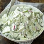 Creamy cucumber salad in a bowl with cucumbers, dill, red onions and creamy sour cream dressing