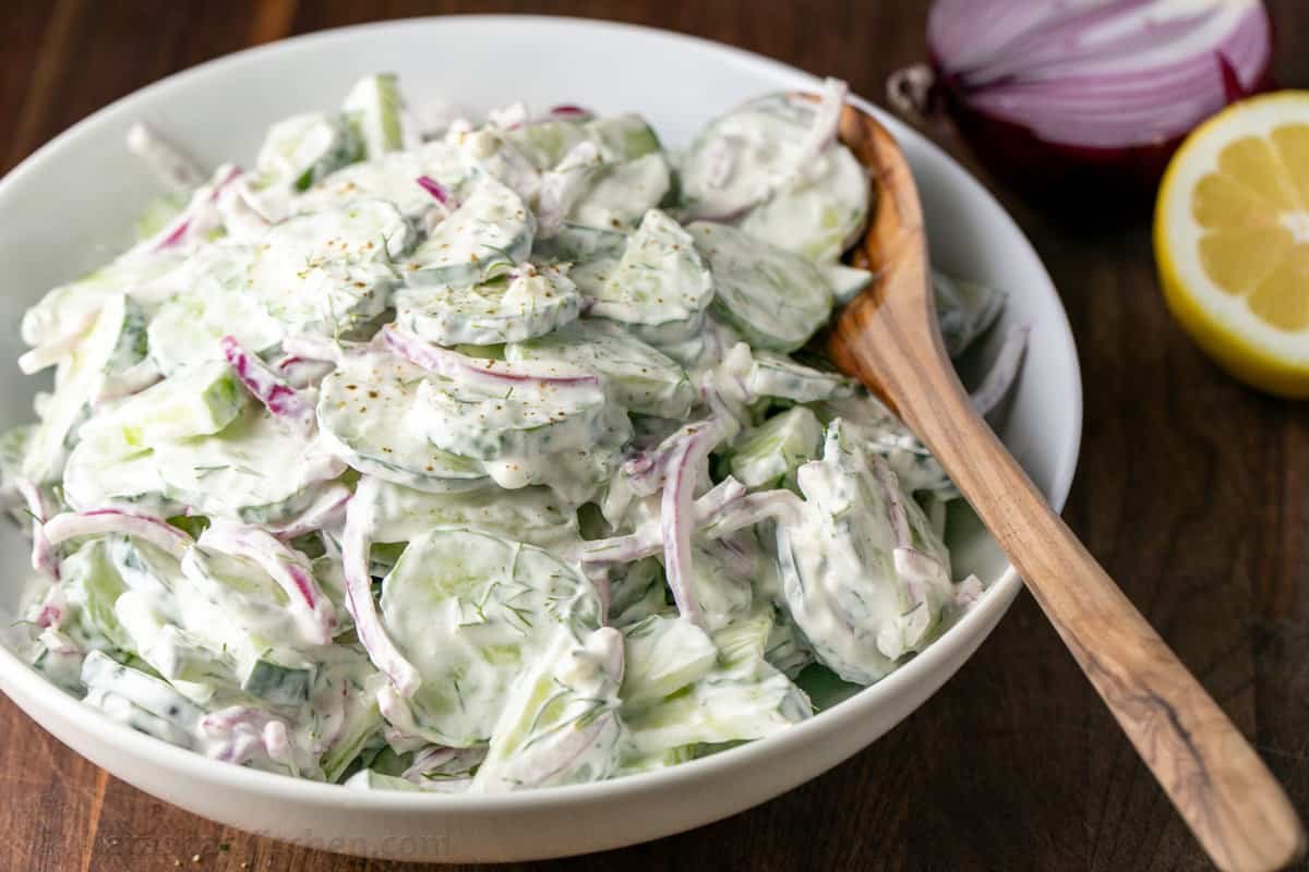 This easy Creamy Cucumber Salad combines cucumbers and red onions with a sour cream, lemon, and dill sauce that won't be able to resist! Close up of a creamy summer side dish with cucumbers, sour cream dressing, fresh lemon juice and red onions