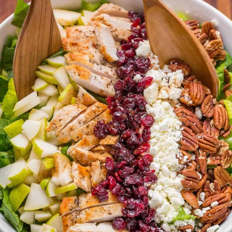 A bowl of autumn chopped chicken salad with two wooden spoons in the bowl