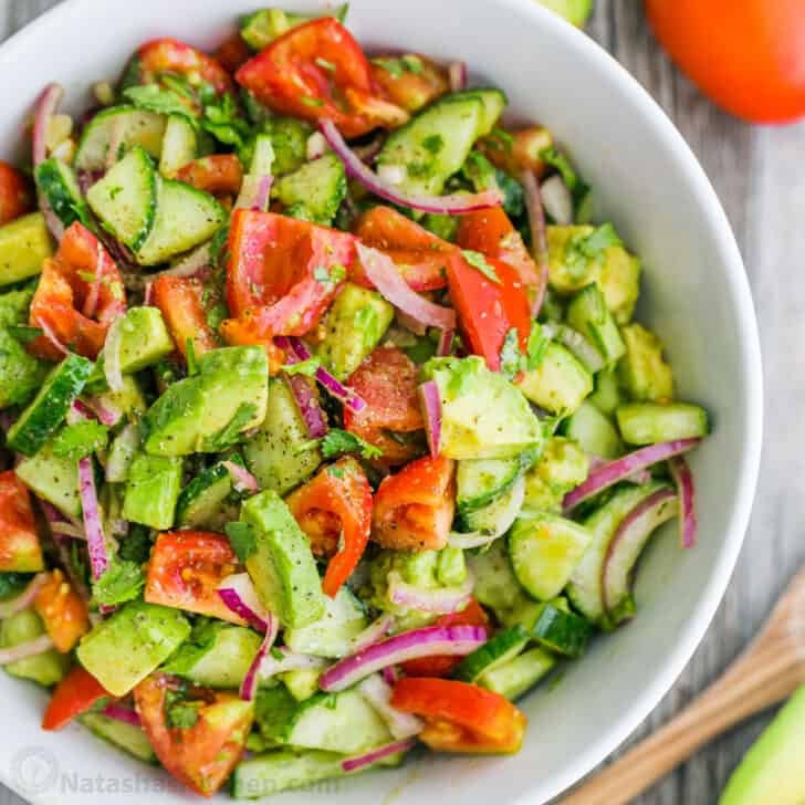 Cucumber tomato avocado salad in white serving bowl