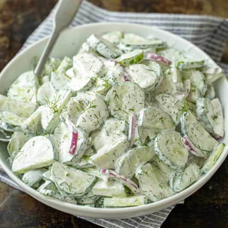 Creamy cucumber salad in a bowl with cucumbers, dill, red onions and creamy sour cream dressing