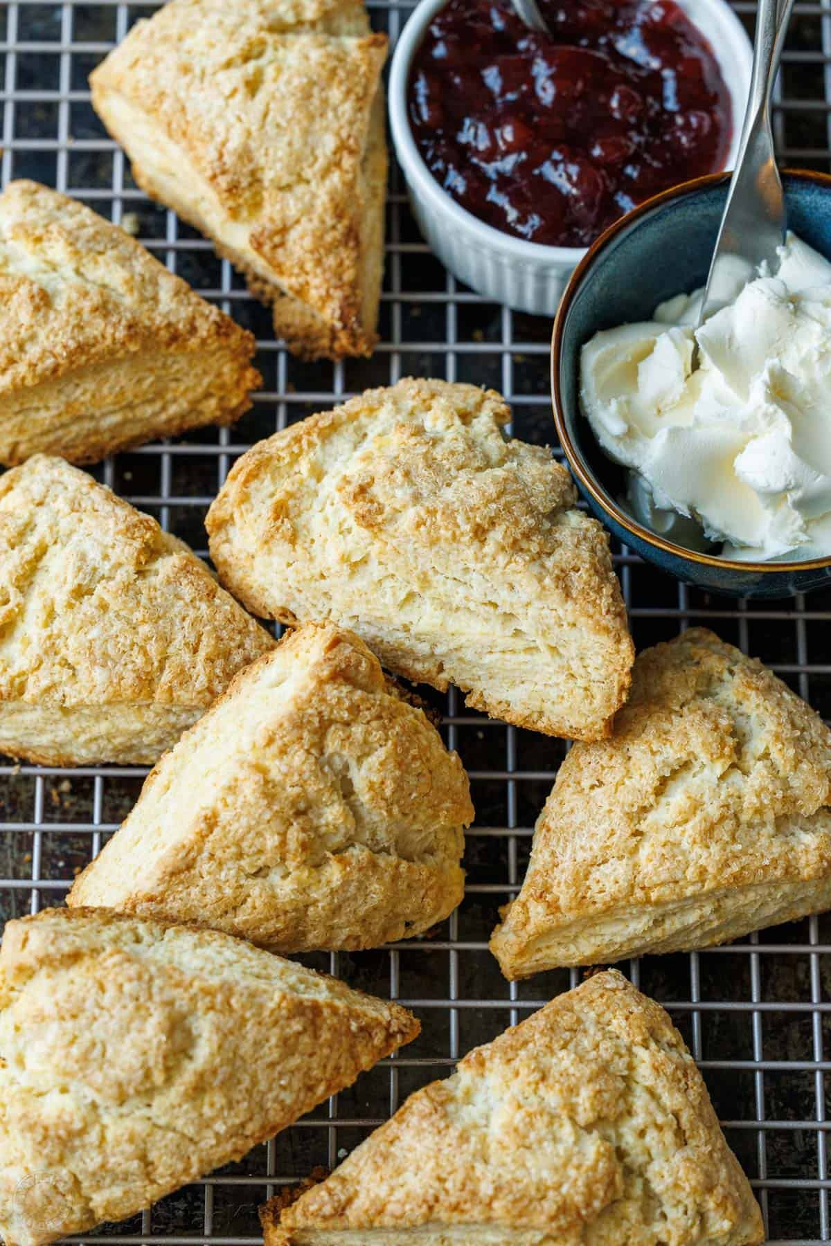This classic Scone recipe is the perfect base for any homemade scones. Create delicious variations that will rival your favorite coffee shop scones. Classic scones on a wire cooling rack with clotted cream and jam in ramekin dishes to use as toppings