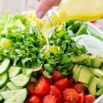 A bowl of Mexican salad with a lime dressing being poured over the salad