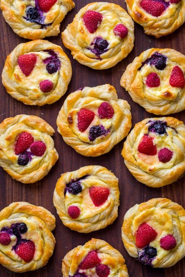 This Cream Cheese Danish recipe is so easy to make. The cheese danish filling tastes just like cheesecake and the fresh berries and lemon glaze add a bright pop of flavor. This puff pastry recipe always disappears fast! | natashaskitchen.com Baked cream cheese danish cooling to room temperature without lemon glaze