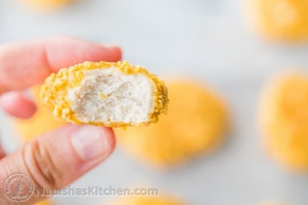 Baked chicken nugget made with chicken breast bitten into showing the tender center
