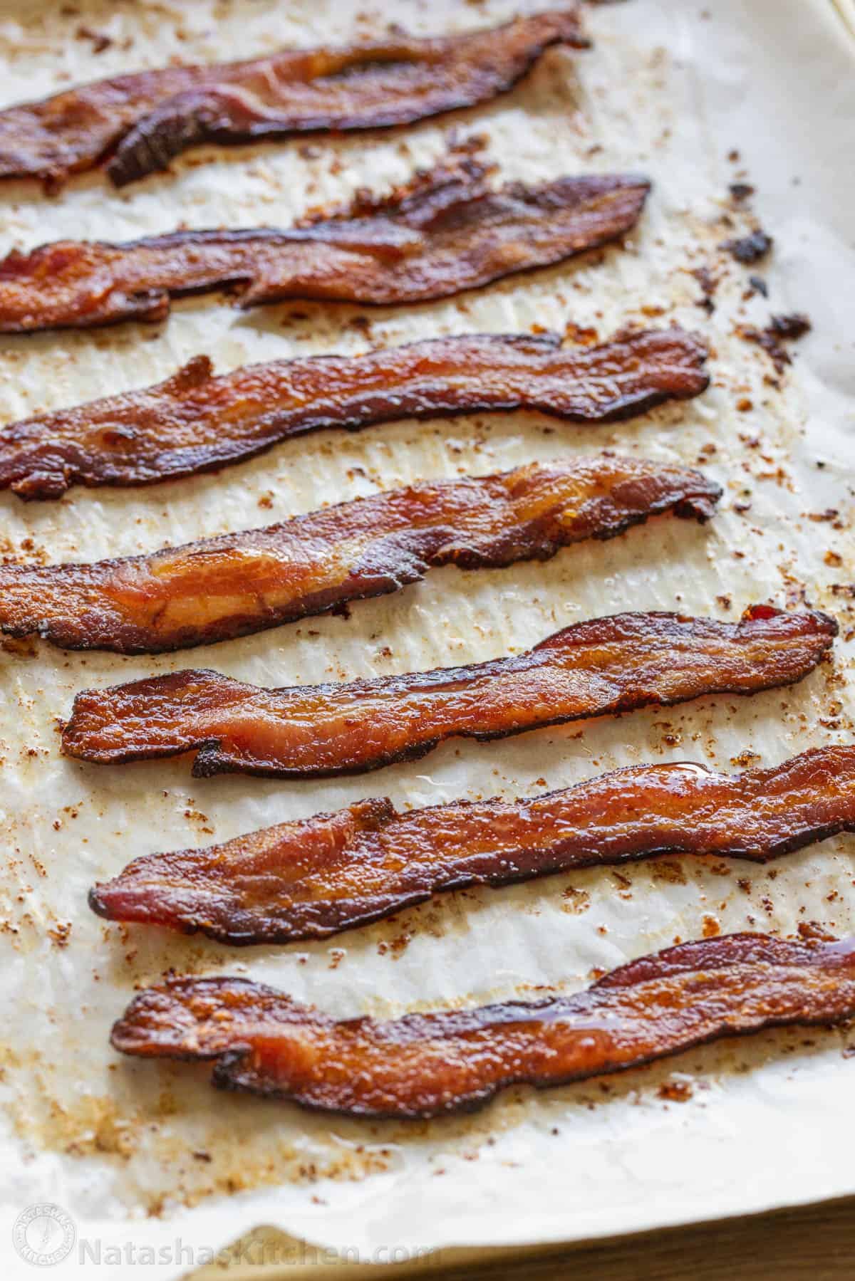 How to bake bacon in the oven that is perfectly crispy. Oven-baked bacon is the best for making a bigger batch and it's the easiest method. slices of baked bacon on a baking tray