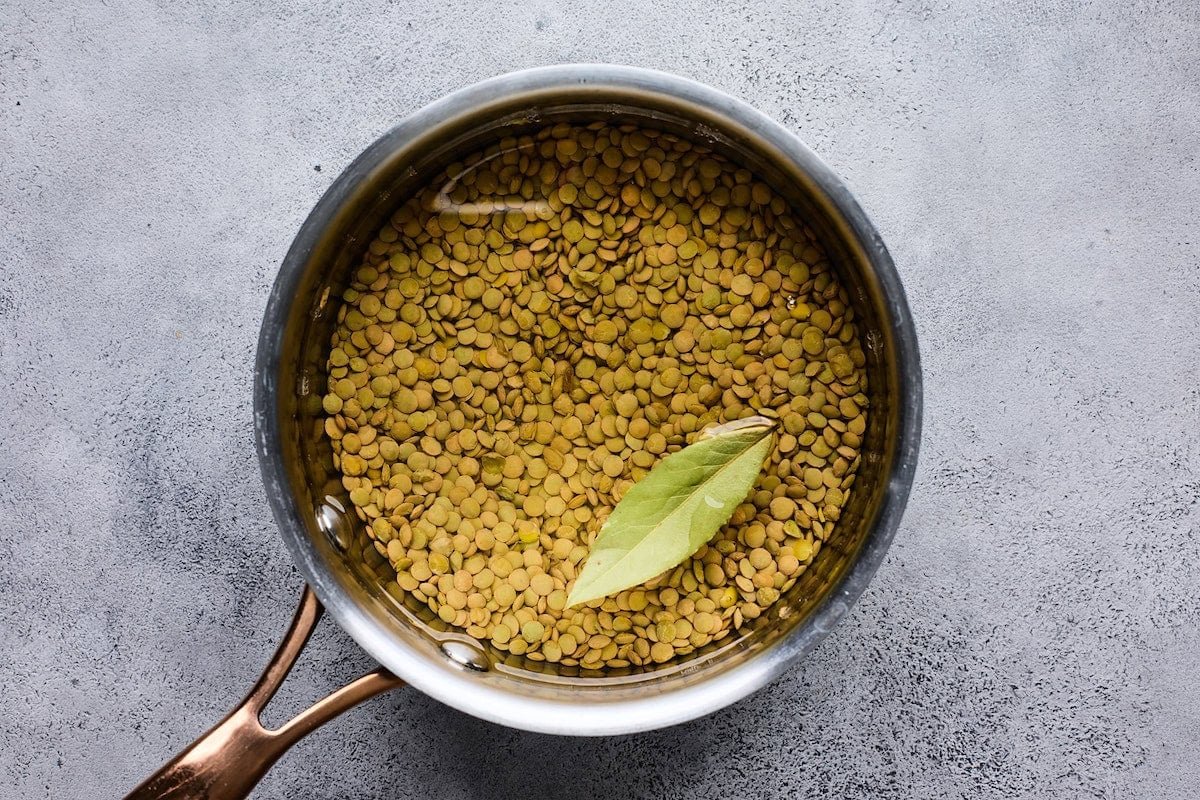 lentils cooking in pot with bay leaf.