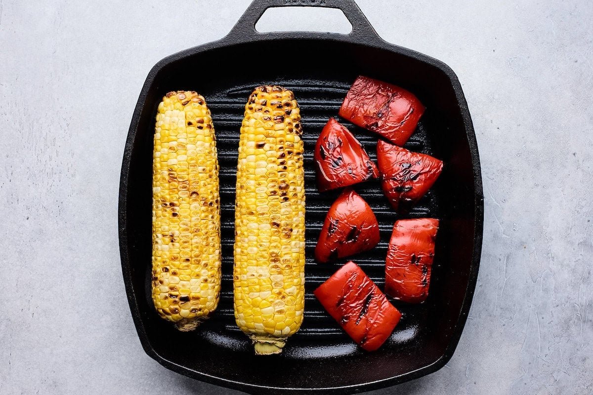 sweet corn and red bell peppers grilling on grill pan.