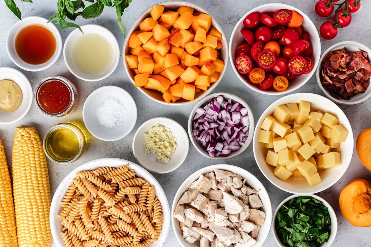 ingredients in bowls to make chicken bacon peach pasta salad with hot honey dressing.
