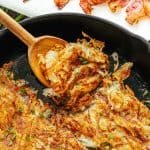 Crispy hash brown recipe on a skillet with a serving spoon