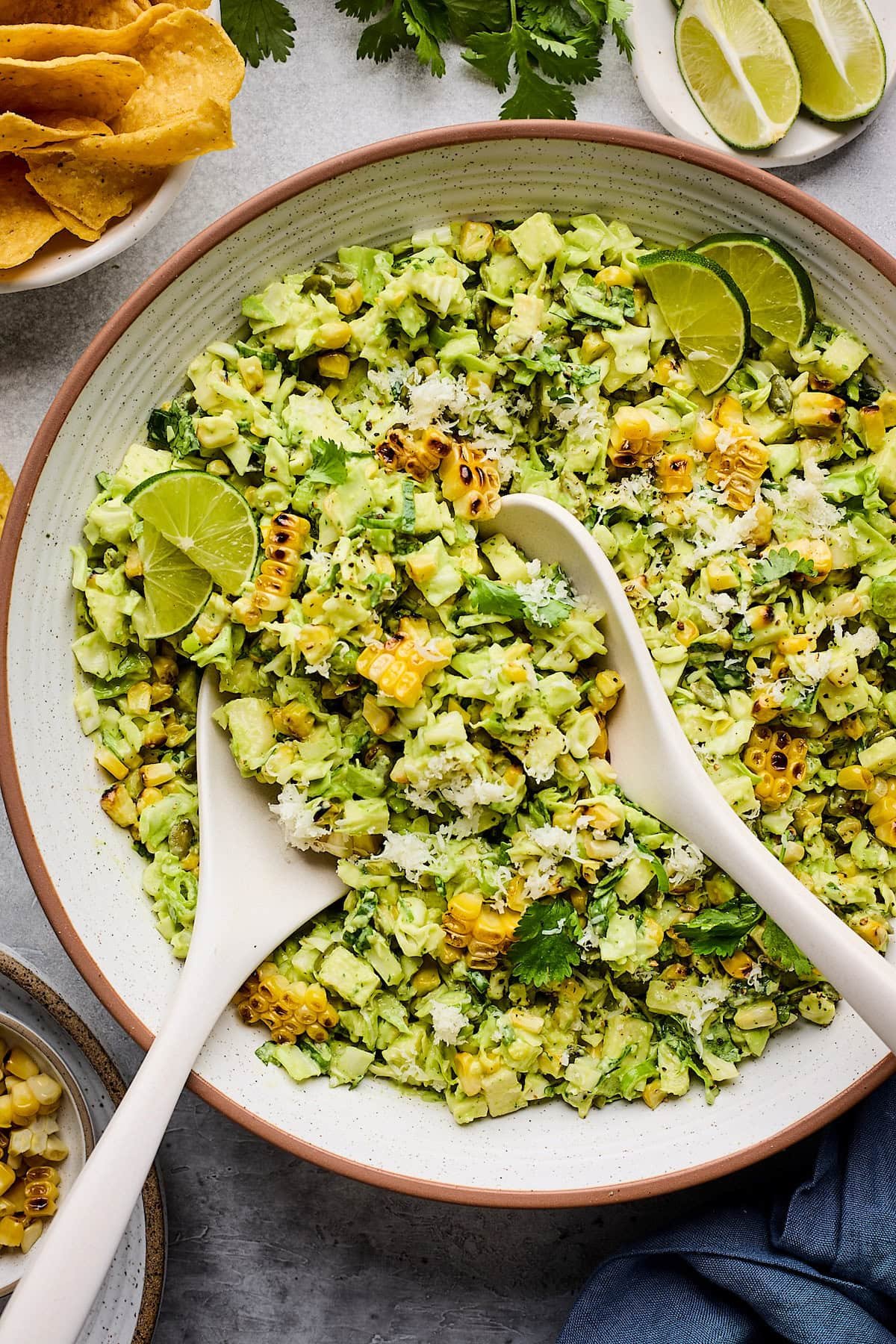 charred corn cabbage salad with creamy avocado dressing with serving spoons in big bowl.