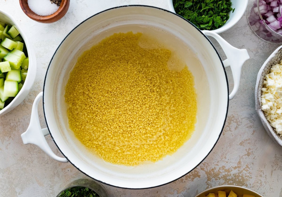 couscous cooking in water in large white pot.