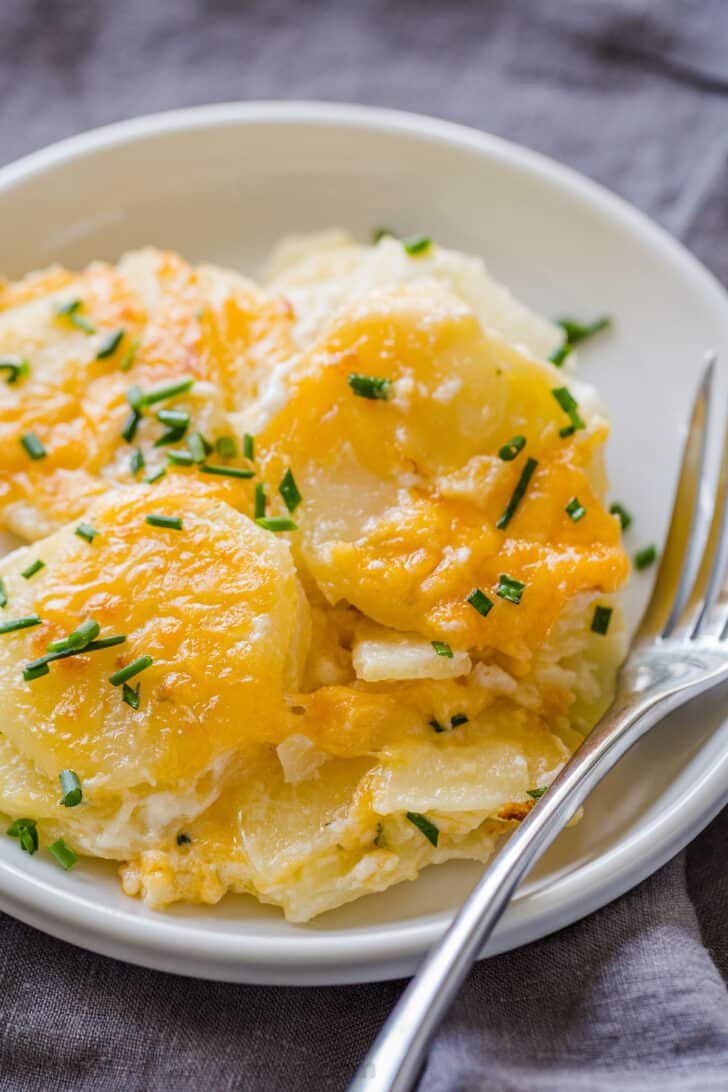 Creamy, cheesy, and easy Scalloped Potatoes Recipe. This holiday-worthy potato side dish has few ingredients and comes together quickly. #scallopedpotatoes #potatocasserole #potatobake Plated scalloped potatoes side dish