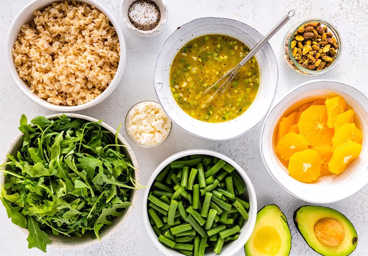 ingredients in bowls to make orange arugula salad.