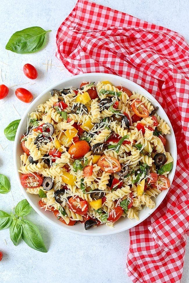 This Easy Pasta Salad is perfect for summer potlucks, parties, and picnics. It is SO easy to make and always a hit! #pasta #pastasalad #summer #vegetarian #easyrecipe #vegetarianrecipe #recipe Pasta Salad with tomatoes, peppers, olives, basil, and Parmesan cheese in bowl.