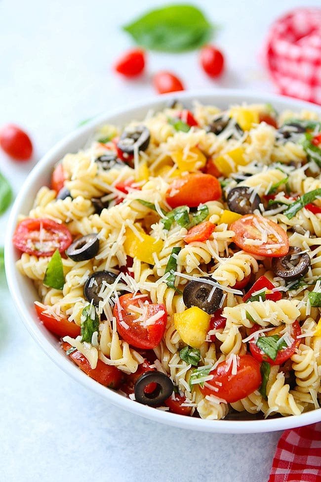 This easy pasta salad is a summer favorite! Perfect for easy dinners or take to a bbq, potluck, or picnic! #pasta #pastasalad #easyrecipe #dinner #vegetarian #recipe #summer #bbq #picnic Easy Pasta Salad in bowl with veggies, basil, and Parmesan cheese.