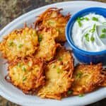 Latkes fried and topped with chives. On a plate with sour cream