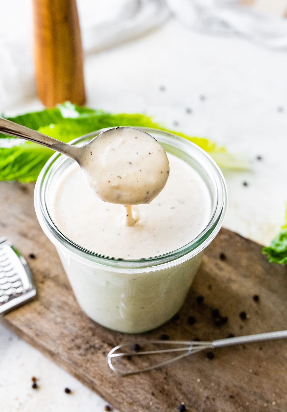 caesar dressing in jar with spoon stirring it.