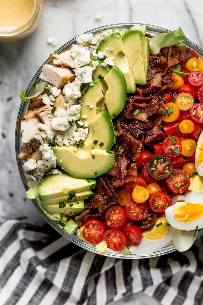Cobb Salad With Chicken, Bacon, Tomatoes, Hard Boiled Eggs, Avocado, Blue Cheese, Chives, And A Simple Red Wine Vinegar Dressing. This Traditional Cobb Salad Is Loaded With Goodness And Always A Favorite! #salad #bacon #chicken #chickenrecipe #cobbsalad #avocado #eggs #glutenfree #glutenfreerecipe Cobb Salad with chicken, blue cheese, avocado, bacon, tomatoes, and hard boiled eggs in a large bowl.